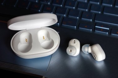 Bilgisayarında şarj aleti olan kablosuz bluetooth kulaklık. Yakın plan.