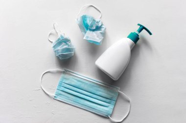 Yeni ve kullanılmış tıbbi maskeler, ve beyaz arka planda antiseptik jel, ikinci dalga covid 19