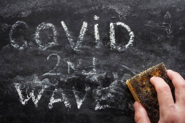 Siyah arkaplandaki ikinci dalga covid yazısını siler
