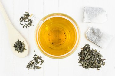 Kağıt poşet yeşil çay ve tahta kaşık beyaz bir tablo.