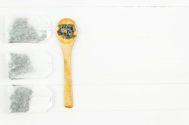 Kağıt poşet yeşil çay ve tahta kaşık beyaz bir tablo.