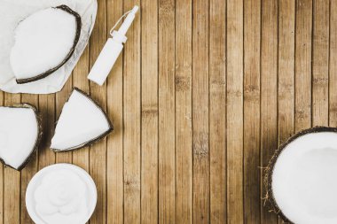 Hindistan cevizi parçaları ve kozmetik ahşap bir masa üzerinde. Hindistan cevizi sütü krema ve tereyağı. Metin için yer kopyalayın