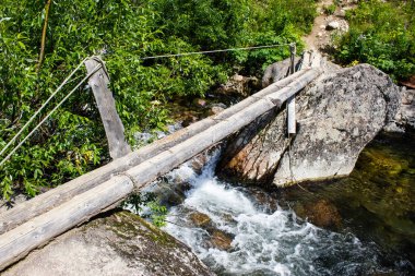 Woods ve ipleri dağ nehirden yapılmış eski ahşap Turizm Köprüsü.