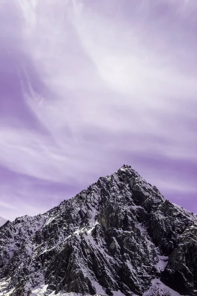 冬季山中的黎明或日落 粉红云下的山脉 岩石上覆盖着雪和紫色的天空 — 图库照片