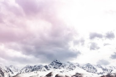 Pembe bulutlar dağ aralığı boyunca. Taşların altında kar ufukta. Dağ Vadisi günbatımı