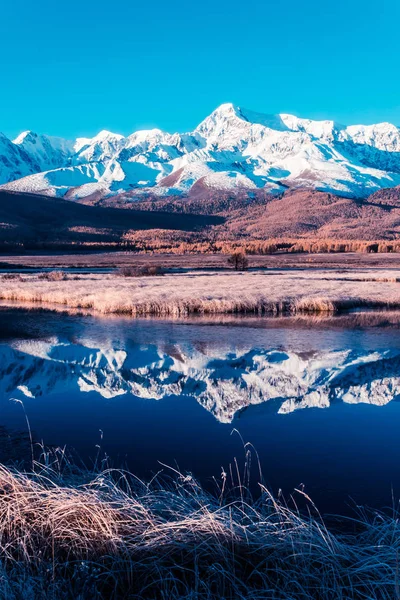 Reflection of snowy mountain ridge in lake. Autumn in mountains. Travel Altai.