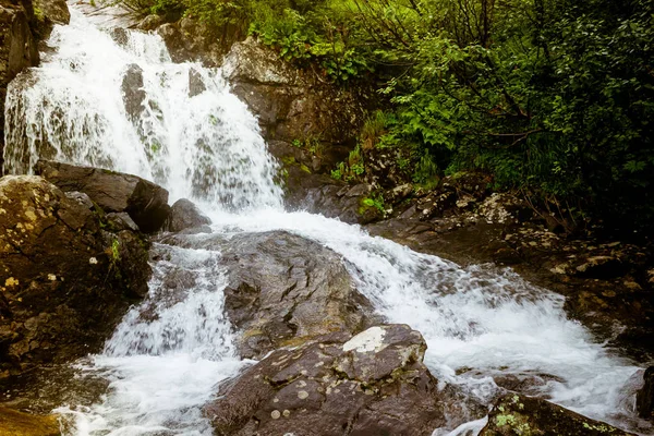 Waterfall in mountains. Rapid flow in river. Water in rocks, trip along river.