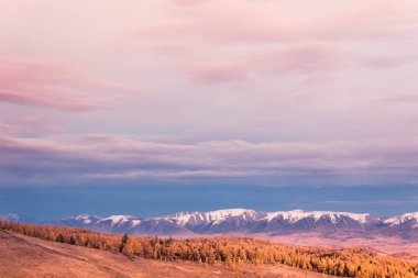 Pembe ve mor bulutlar dağ aralığı boyunca. Gün batımı veya sonbaharda dağlarda şafak. Dağlar Vadisi için yürüyüş gezisi.