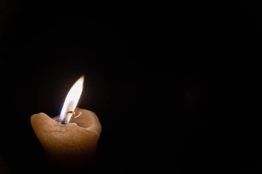 Yalnız anıt mum. Mum alevi karanlıkta yanar.