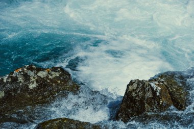 Mavi sularda taşlı bir dağ nehri. Turkuaz deniz gelgiti dalgaları