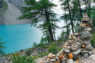Mavi göl kıyısındaki turistler için taş yığını. Yaz günü deniz kayalıkları kıyısı. Doğa üzerine meditasyon