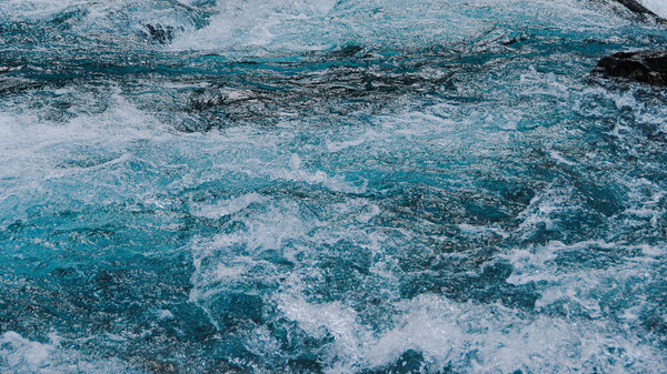 Blue bubbling water of mountain river. Ocean tide of  turquoise sea