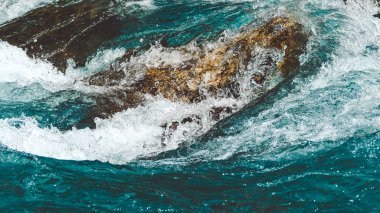 Taştan kıyısı olan nehirde turkuaz su. Deniz gelgiti, dağ deresinde kaynayan mavi su.