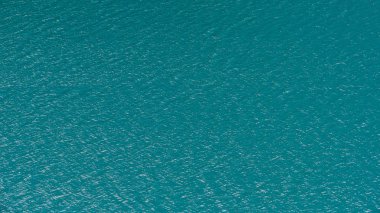 Mavi suyla gölün pürüzsüz yüzeyi, arkaplan olarak turkuaz deniz.