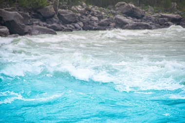 Mavi kaynayan su kayalara, deniz sörfüne, dağ nehrinin hızlı akışına, okyanus dalgalarına çarpar.