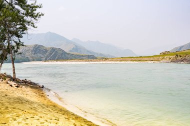 Dağ vadisinde nehir, taşların ve kayaların arasında su akıntısı, kıyıda ağaçlar, salda su turisti gezisi.