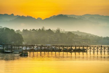 Eski ahşap köprü (Mon Köprüsü) gündoğumu, Kanchanaburi Eyaleti, Tayland nehirde ortasında.