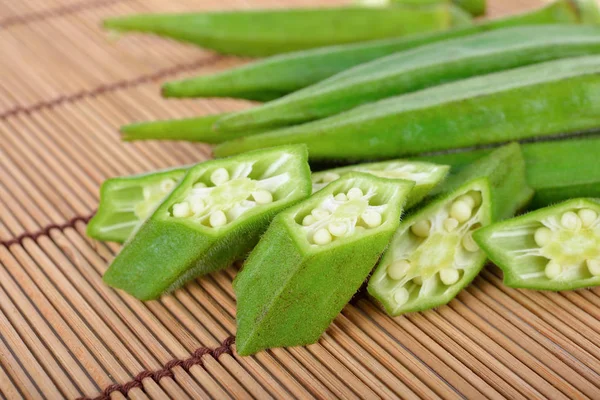 Okras Frais Entiers Coupés Par Portion Sur Fond Tapis Bois — Photo