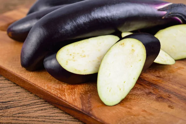 Bütün ve dilimlenmiş taze mor patlıcan ahşap kesim bo