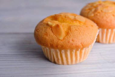 ahşap backgr üzerinde kağıt bardak dilimlenmiş badem ile muffin fincan kek