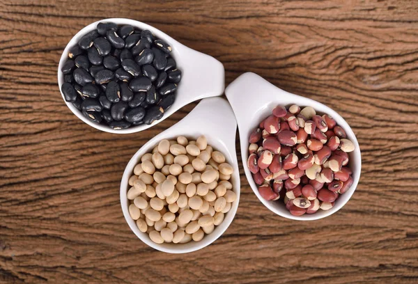 top view navy beans, cowpeas and black beans in ceramic cup on w