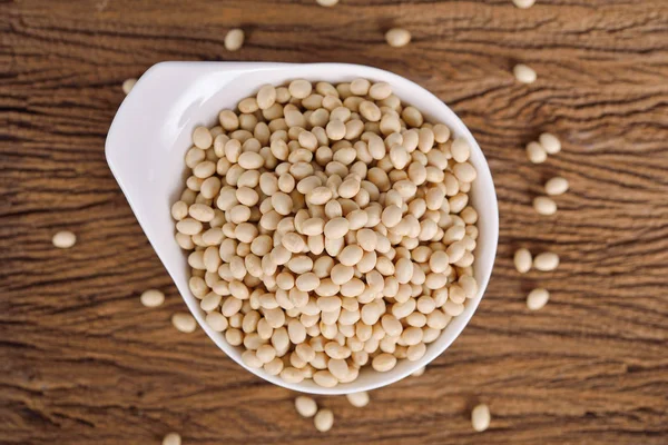 Uncooked navy beans in white bowl and on wooden background Royalty Free Stock Photos