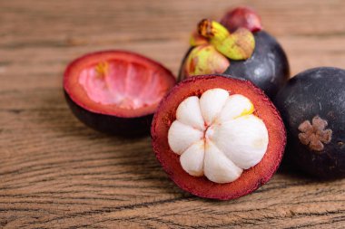 Ahşap masanın üzerinde bir buçuk parça olgun Mangosteen.
