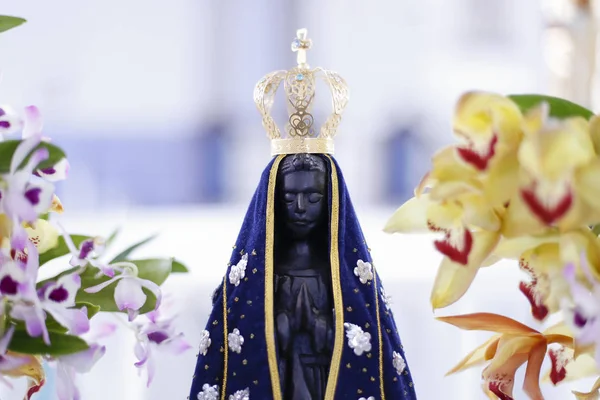 Statue of the image of Our Lady of Aparecida, mother of God in the Catholic religion, patroness of Brazil, decorated with flowers and orchids