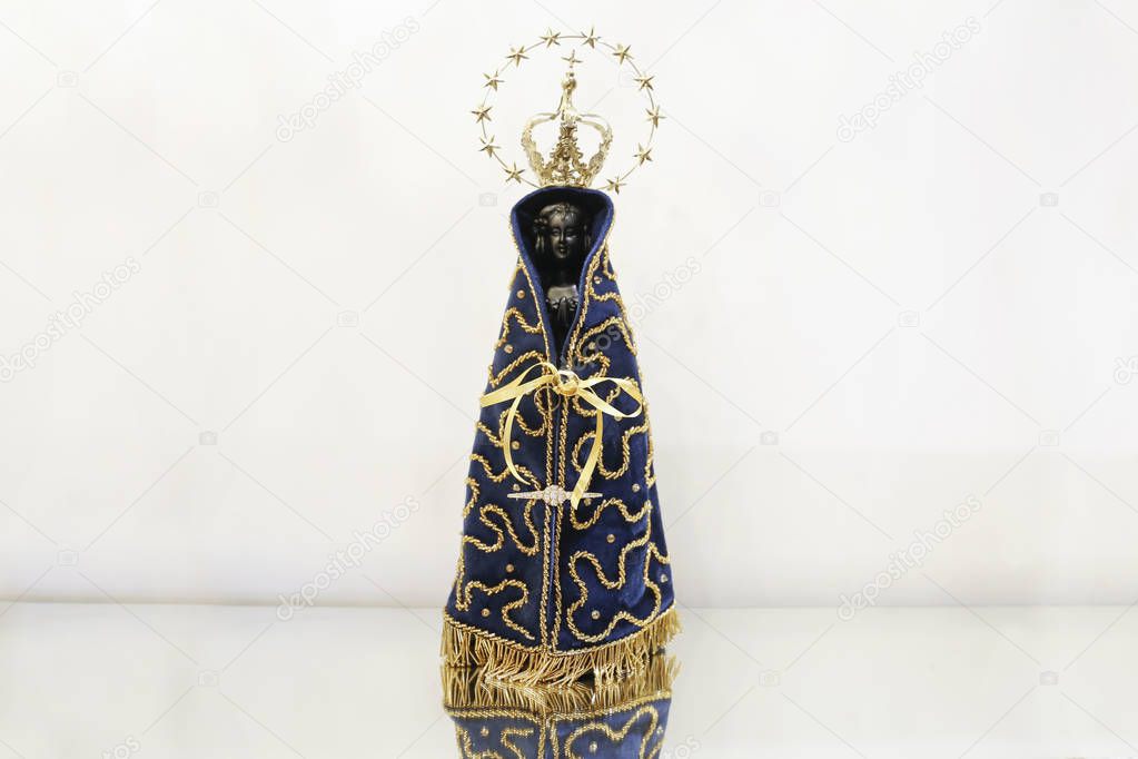 Statue of the image of Our Lady of Aparecida, mother of God in the Catholic religion, patroness of Brazil, isolated, with alliances, in a neutral background environment