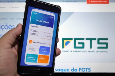 Minas Gerais / Brezilya - 15 Haziran 2020: Caixa bankası FGTS acil finansal çekilme başvurusu ile bilgisayar ekranı ve cep telefonu.