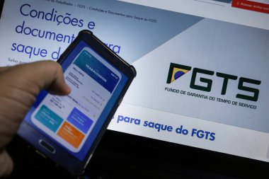 Minas Gerais / Brezilya - 15 Haziran 2020: Caixa bankası FGTS acil finansal çekilme başvurusu ile bilgisayar ekranı ve cep telefonu.