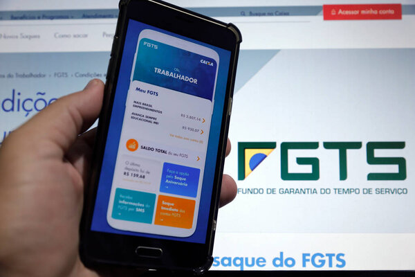 Minas Gerais / Brazil - June 15, 2020: computer screen and cell phone with Caixa bank FGTS application for emergency financial withdrawal.
