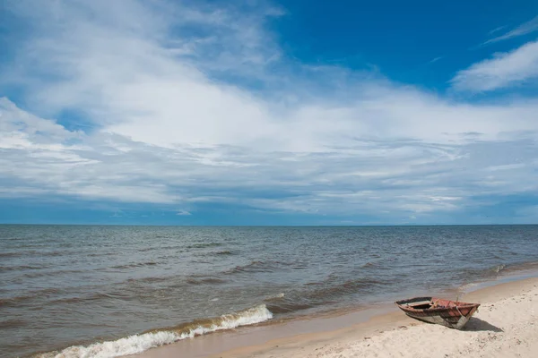 Wooden boat on the sandy shore of lake Baikal, blue sky and calm water.