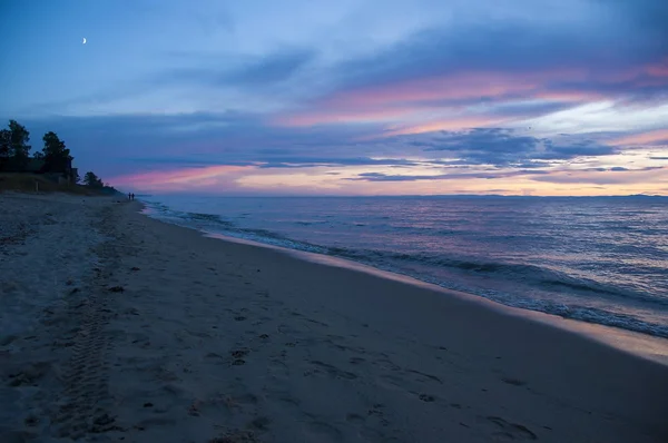 İnsanlar gün batımında Baykal Gölü sahilinde yürüyorlar..