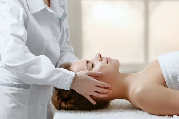 Médico massagista terapeuta faz massagem médica e relaxante para a menina no paciente em salão de massagem leve — Fotografia de Stock