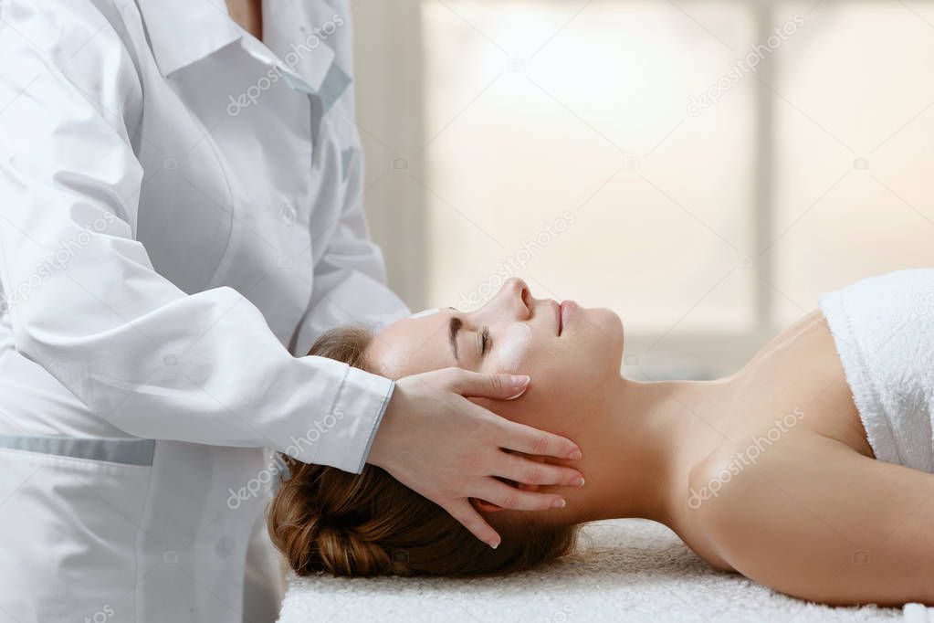 Doctor masseur terapist makes medical and relaxing massage for girl in patient in light massage parlor