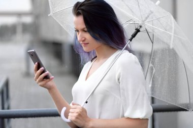 Kadın konuşmak için şemsiye ile cep telefonu