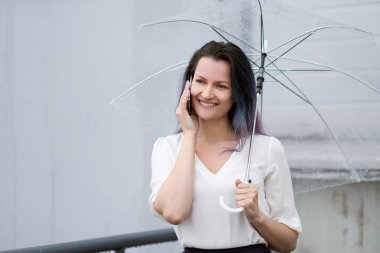 Kadın konuşmak için şemsiye ile cep telefonu