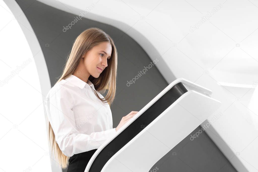 Young beautiful girl uses a touch screen computer terminal on a white background.