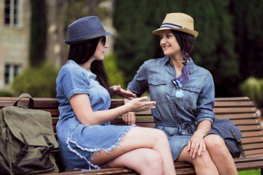 iki güzel genç kadın parkta bir bankta oturan