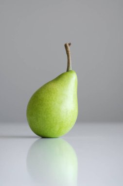 Beyaz bir tablo, bir yansıması, bir parlak ışık, minimalizm ve metin için boş alan bir Yeşil Sarı armut bir dal ile standları.