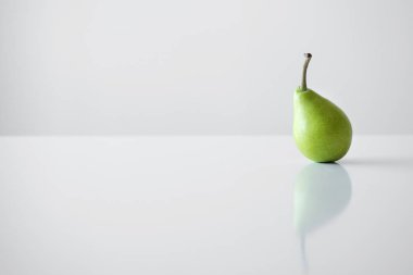 Beyaz bir tablo, bir yansıması, bir parlak ışık, minimalizm ve metin için boş alan bir Yeşil Sarı armut bir dal ile standları.
