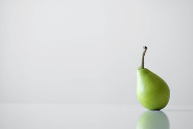 Beyaz bir tablo, bir yansıması, bir parlak ışık, minimalizm ve metin için boş alan bir Yeşil Sarı armut bir dal ile standları.