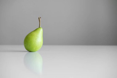 Beyaz bir tablo, bir yansıması, bir parlak ışık, minimalizm ve metin için boş alan bir Yeşil Sarı armut bir dal ile standları.
