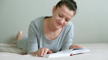 Genç esmer kız yatakta yatarken kitap okuma.