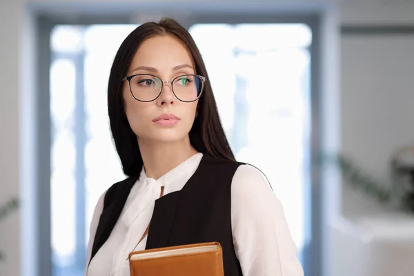 Dziewczyna student lub nauczyciel w biurze. Okulary i kostium, w rękach notebooka. — Zdjęcie stockowe