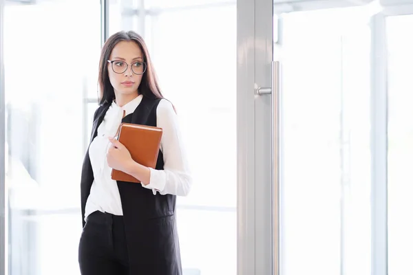 Una joven hermosa chica en gafas entra en la puerta de la oficina de cristal . — Foto de Stock