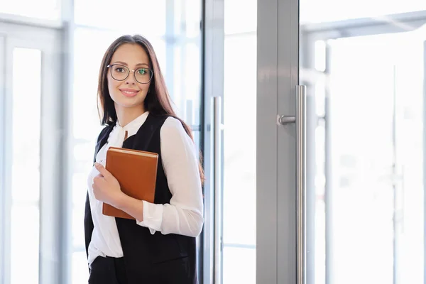 Una joven hermosa chica en gafas entra en la puerta de la oficina de cristal . — Foto de Stock