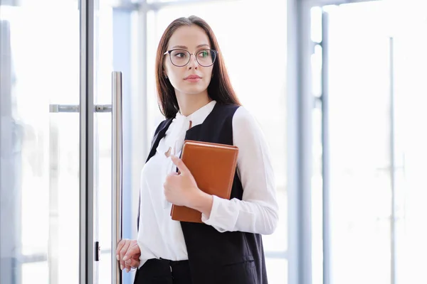 Güzel bir genç kız gözlük içinde cam ofis kapı girer.