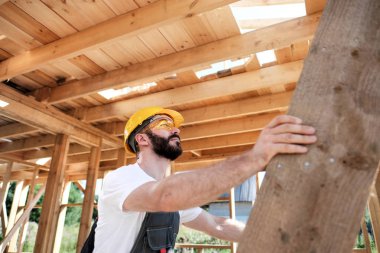 Adam bir ahşap çerçeve ev çatısında bir kurucusudur.